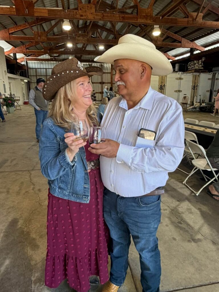 two people clinking their glasses and smiling wearing cowboy hats